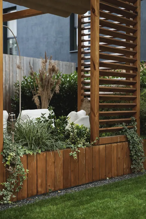 Pergola z lamelami i drewnianą donicą pełną zieleni